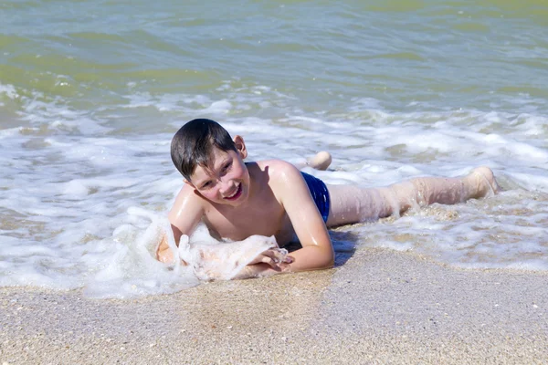 Мальчик лежит на пляже в серфинге — стоковое фото