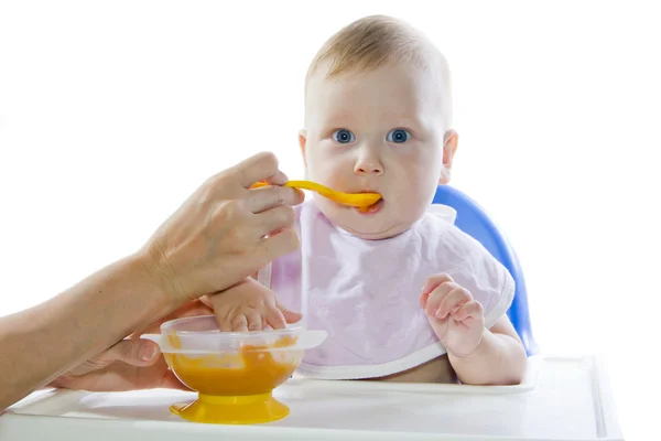 Молодой голубоглазый ребенок кормит тыквенное пюре — стоковое фото