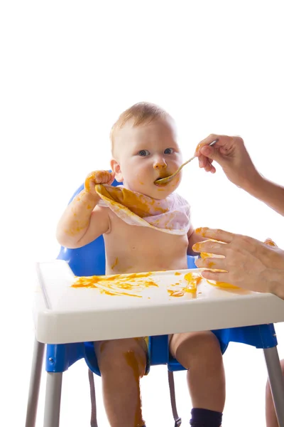 Een jonge blauwogige kind voeding pompoen puree — Stockfoto