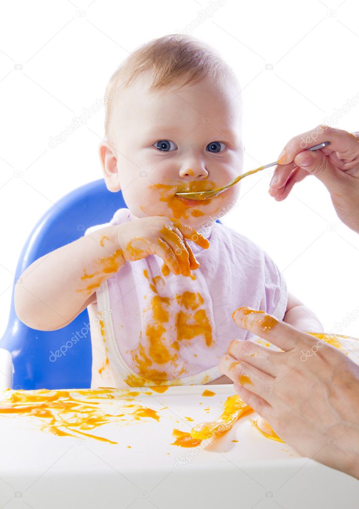 A young blue-eyed child feeding pumpkin puree