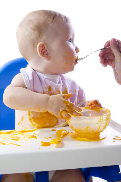Nuori sinisilmäinen lapsi ruokkii kurpitsan sose — kuvapankkivalokuva