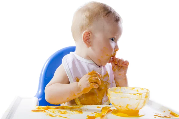Een jonge blauwogige kind voeding pompoen puree — Stockfoto