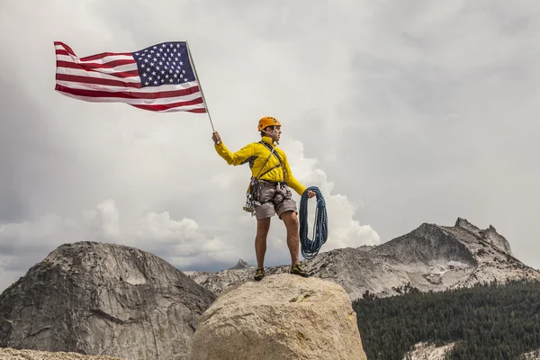 Climber raising the flag on the summit. — Stock Photo, Image