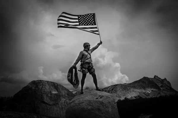 クライマーは頂上に旗を上げる. — ストック写真