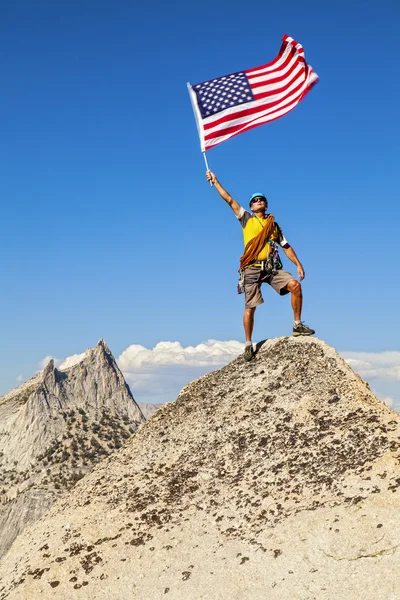 Bergsteiger schwenkt Fahne auf Berggipfel. — Stockfoto