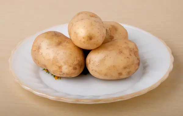 Batatas frescas em um prato branco — Fotografia de Stock