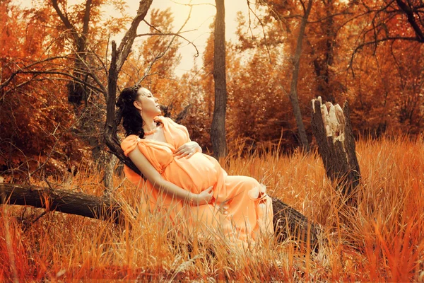 Pregnant woman in red forest — Stock Photo, Image