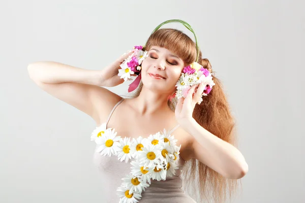 Дівчина слухає музику в навушниках з квітами — стокове фото