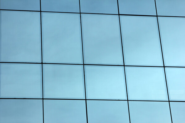 This is a glass office building reflecting the blue sky.