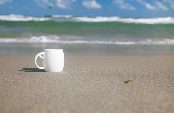 Кофе эспрессо в белой чашке с океанскими волнами, пляжем и морской шапкой — стоковое фото