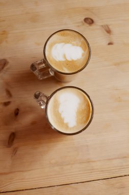 Coffee latte in two tall glasses on wood, shallow dof clipart