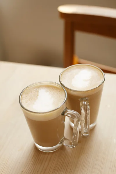 Kawa latte w wysokości dwóch okulary woden stół i krzesła — Zdjęcie stockowe