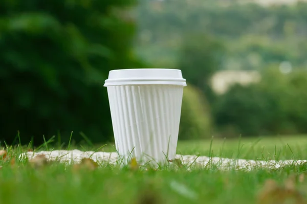 Uma xícara de café branco na grama, rasa DOF — Fotografia de Stock