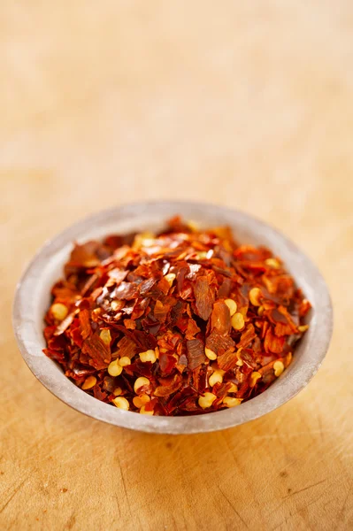 Hot Red Chilli Chillies pepper crushed in tin bowl on wood — Stock Photo, Image