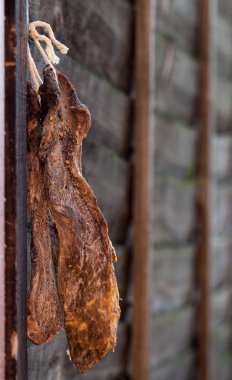 Biltong - dry cured meat on a wooden fence clipart
