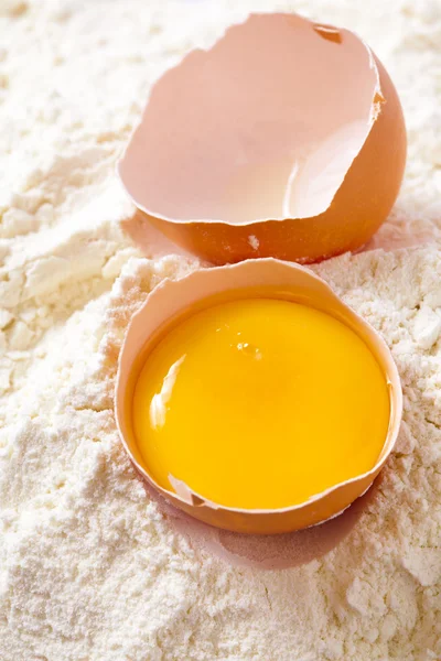 Zerbrochenes Ei mit Schalen auf Mehl — Stockfoto