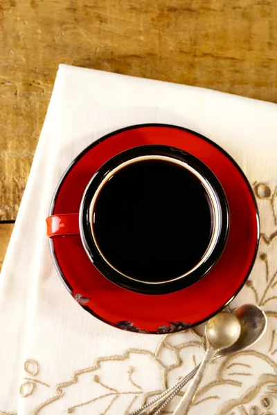 Café negro, taza de esmalte rojo, dos cucharas de plata viejas en bordado —  Fotos de Stock