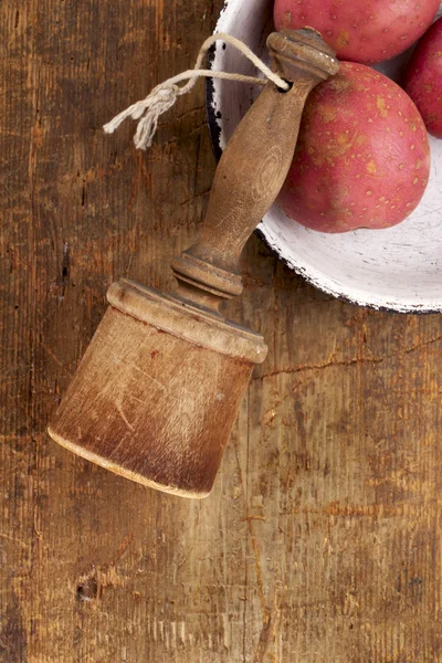 Retro potato masher on old wooden table with potato — Stock Photo, Image