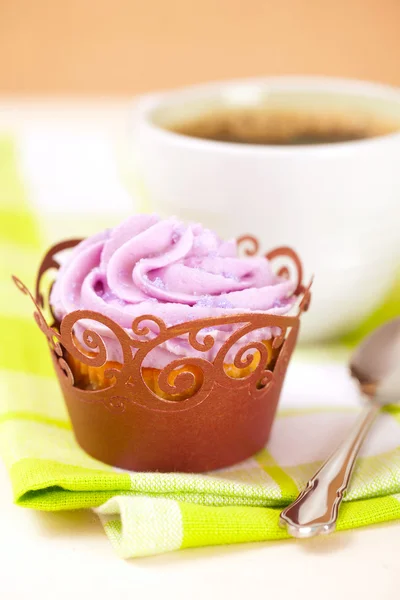 Кекс с лавандовым глазурью в праздничной обертке и чашке кофе — стоковое фото