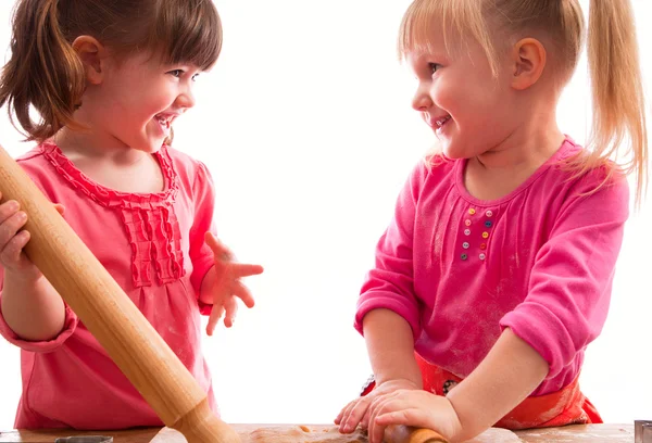 Two little girls with rolling pins baking cookies — Stock Photo, Image