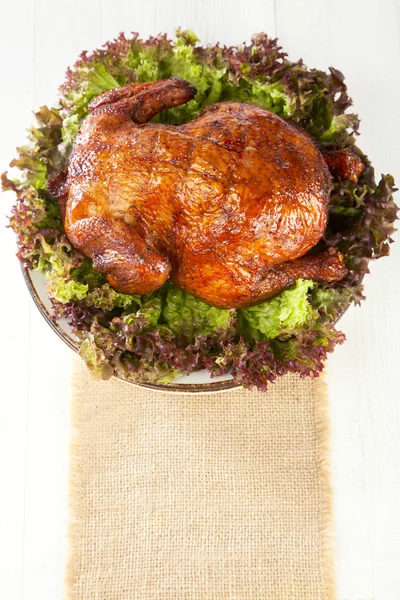 Homemade smoked whole chicken on leaf lettuce bed and plates — Stock Photo, Image