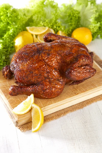 Homemade hot smoked whole chicken on chopping board