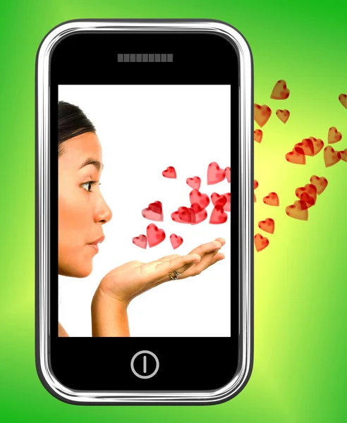 Meisje blazen harten vanaf een mobiele telefoon — Stockfoto