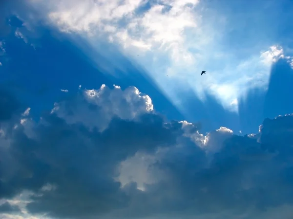 Blå himmel med solens strålar genom molnen — Stockfoto