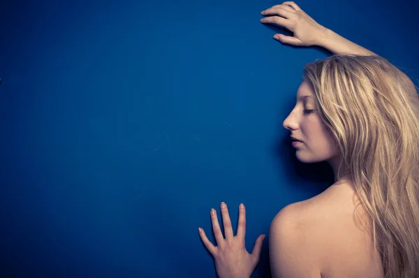 Blond flicka mot blå vägg — Stockfoto