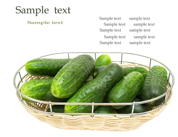 stock image Fresh green cucumber in a wicker plate, isolated on white background.