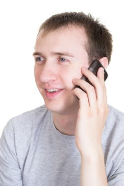 The young man speaks by a mobile phone, isolated on the white background.