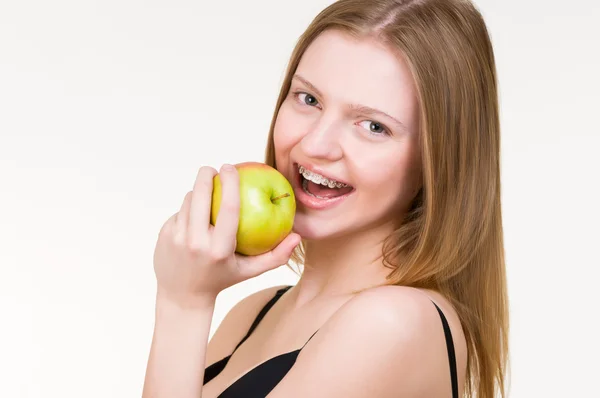 Молода жінка з дужками їсть яблуко — стокове фото
