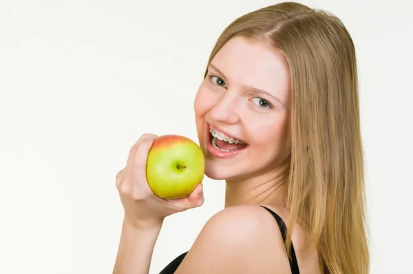 Красива молода жінка з дужками їсть яблуко — стокове фото