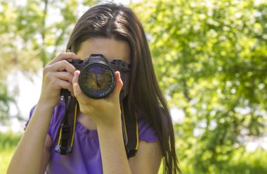 Young girl taking photos at summer green park clipart