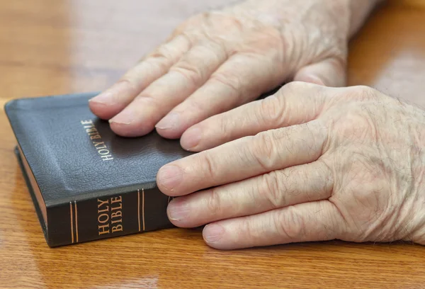 Starý muž ruce na Bibli — Stock fotografie