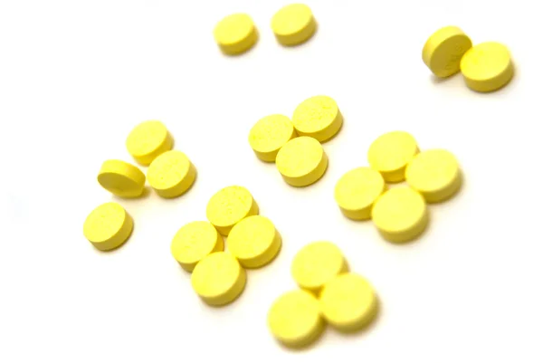 Pílulas amarelas em branco — Fotografia de Stock