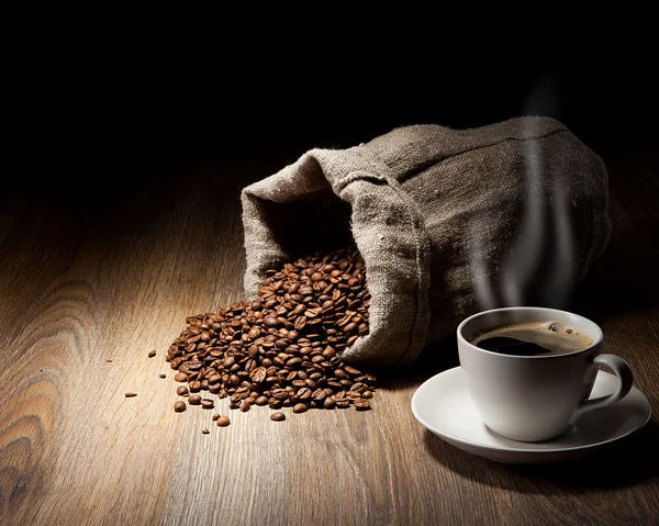 用粗麻布袋咖啡豆仿古桌上的杯咖啡 — 图库照片