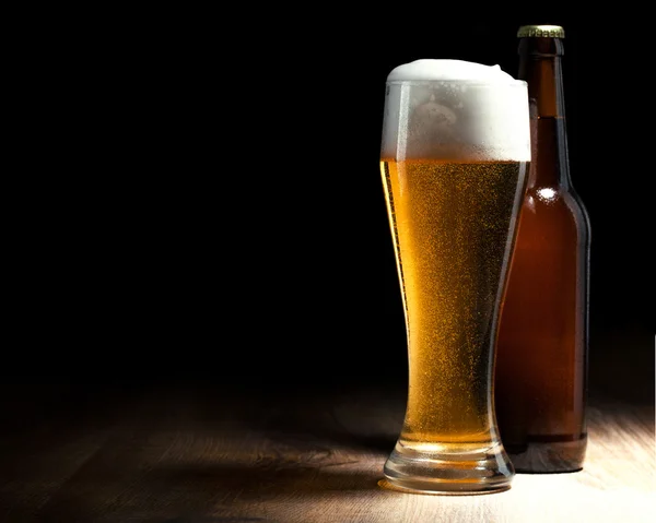 Szkło piwa i butelka na drewnianym stołem — Zdjęcie stockowe