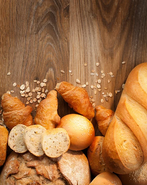 Assortment of baked bread on wood table — Stock Photo, Image
