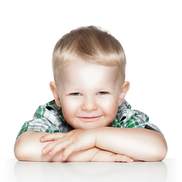 Ritratto di un bambino carino sorridente mentre seduto a tavola, è Fotografia Stock