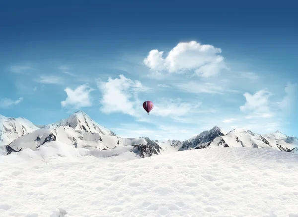 Horská krajina s sněhu a horkovzdušný balón létání v s — Stock fotografie