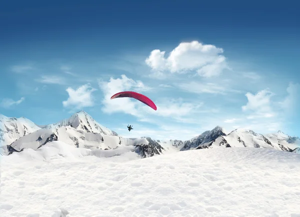 stock image Mountain landscape with snow and man flying in the sky