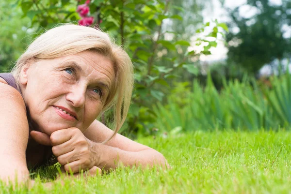 Oude vrouw op gras — Stockfoto