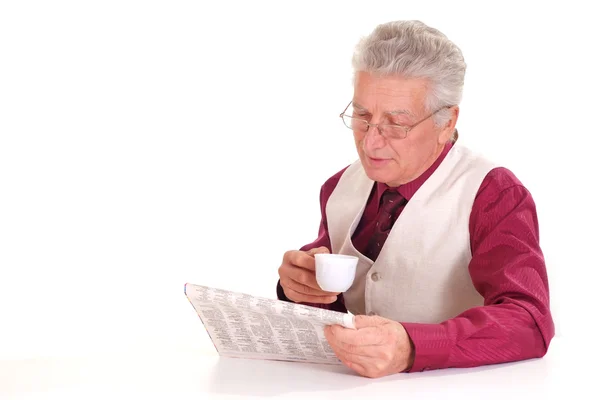 Handsome caucasian old male sits at a table with a newspaper — Stock Photo, Image