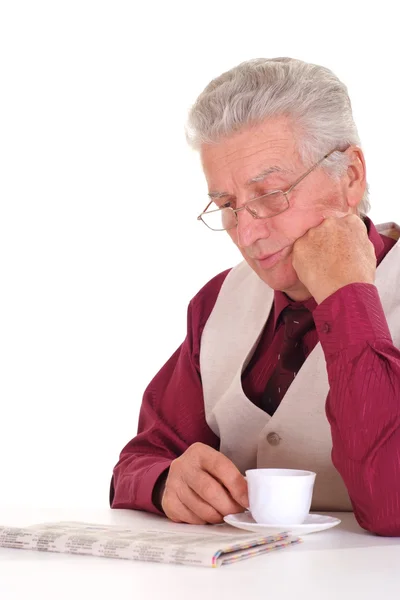 Bonito caucasiano envelhecido macho senta-se em uma mesa com um jornal — Fotografia de Stock