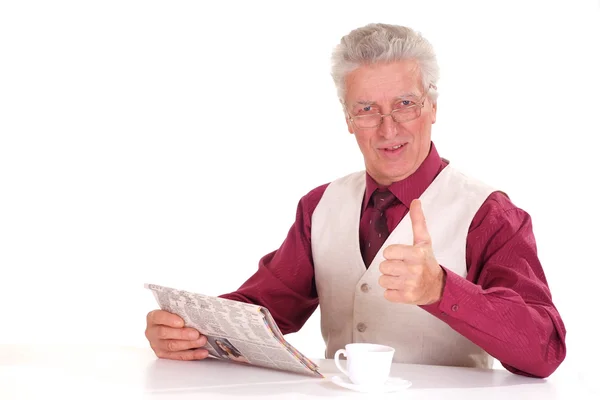 Bonito caucasiano bom homem idoso senta-se a uma mesa com um newsp — Fotografia de Stock