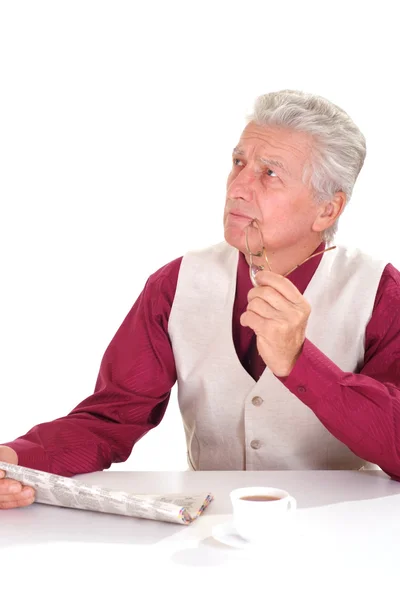 Καυκάσιος όμορφος ευτυχισμένος ηλικιωμένος άνδρας κάθεται σε ένα τραπέζι με μια είδηση — Φωτογραφία Αρχείου