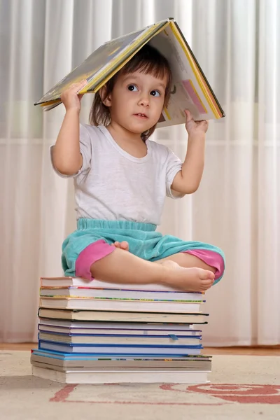 Pequeno bebê caucasiano sentado em uma pilha de livros — Fotografia de Stock