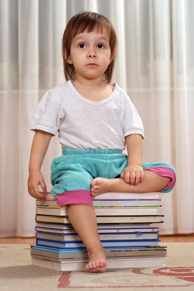 Holčička kavkazské sedí na hromadě knih — Stock fotografie