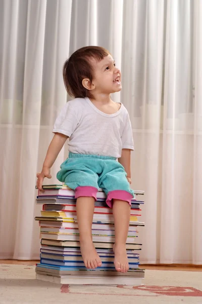 Pequeña chica de la suerte caucásica sentada en un montón de libros —  Fotos de Stock